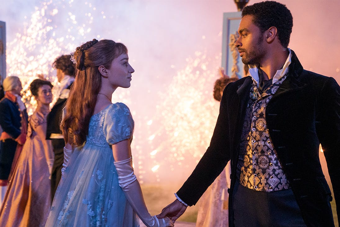 a young man and a woman meet in the middle of the dance floor, fireworks behind them.